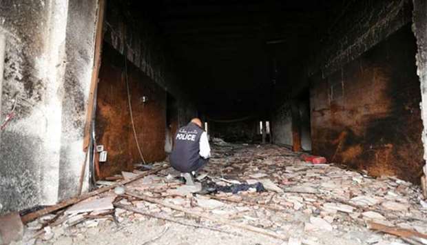 A security personnel inspects the site of a suicide attack on the electoral commission in Tripoli.