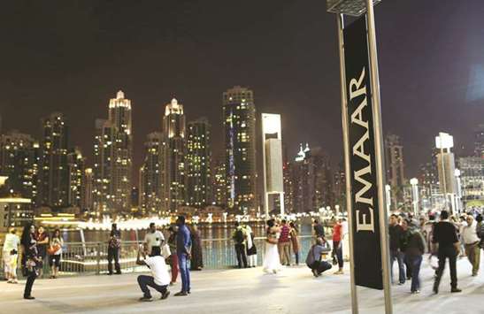People have their pictures taken near an Emaar sign outside the Dubai Mall in Dubai (file). The index of the real estate sector on Dubai bourse has shed around 18% since the start of the year with property giant and market leader Emaar dropping 22%.