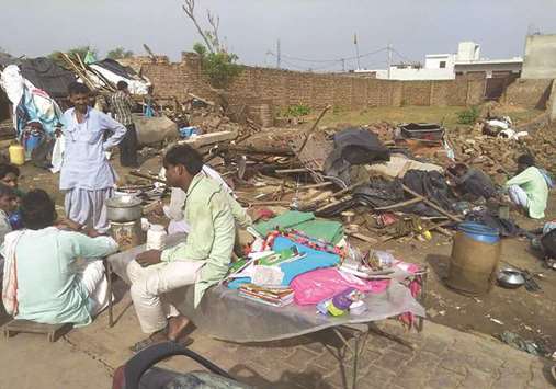 People gather with their belongings next to their destroyed dwellings following a storm in Bharatpur, Rajasthan, yesterday.