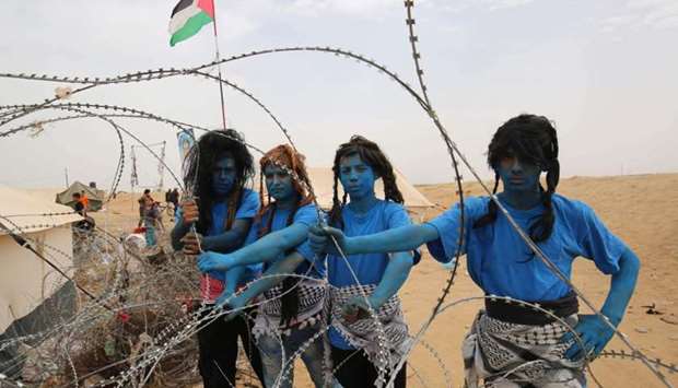 Palestinians with their faces painted like characters from the movie ,Avatar, pose for a picture during a protest demanding the right to return to their historic homelands in what is now Israel, at the Israel-Gaza border, east of Khan Yunis in the southern Gaza Strip.