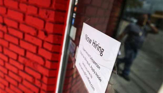 A now hiring sign is seen in the window of a business in Miami, Florida.