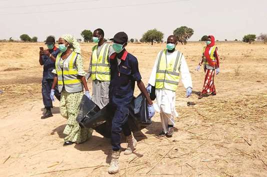 Officials of Borno State Emergency Management Agency carry the body of a victim of multiple suicide attacks to the ambulance in Maiduguri, in northeastern Nigeria, yesterday.