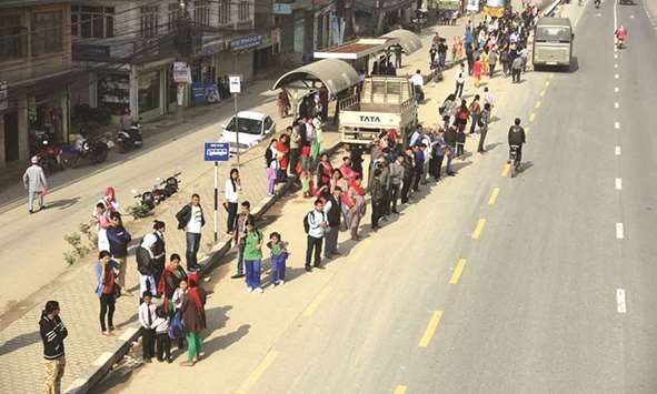 People wait on the roadside for bus to reach their destinations in Kathmandu yesterday.