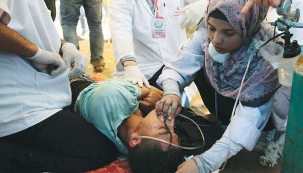 Shorouq Abu Musameh, who volunteers with other paramedics, tends to a Palestinian who inhaled teargas fired by Israeli troops during a protest where Palestinians demand the right to return to their homeland, at the Israel-Gaza border, in the southern Gaza Strip.