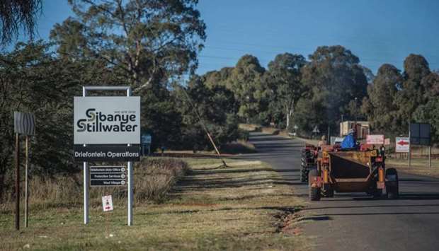 Workers drive past a sign of the Sibanye-Stillwater Driefontein gold mine near Carletonville, near Johannesburg.