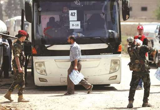 Syrian army soldiers stand near a bus during evacuation at Beit Sahm in Damascus, yesterday.