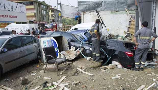 Municipal workers look at the wreckage of piled vehicles pushed against a wall after being washed away during torrential rains and flash flooding in the Mamak district in Ankara on Saturday.
