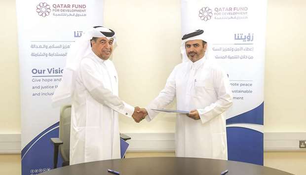 Director of Development Projects at QFFD Misfer Hamad al-Shahwani and Director of Relief and International Development at QRCS Rashid Saad al-Mohannadi exchange documents after signing the agreement.