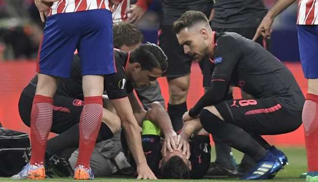 Arsenal's French defender Laurent Koscielny (bottom) lies on the field during the UEFA Europa League semi-final second leg football match between Club Atletico de Madrid and Arsenal FC.