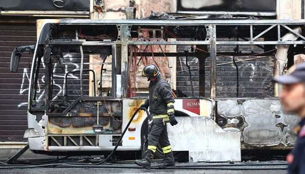 A firefighter walks next to a burned bus in downtown Rome