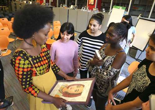 Holding a portrait of herself, Sandra Uwiringiyimana speaks with book club members at Hadley Junior High School in Glen Ellyn.