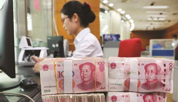 An employee counts 100-yuan notes at a bank in Nantong in Chinau2019s eastern Jiangsu province. The Chinese currency slid to a four-month low yesterday, as jitters increased ahead of pivotal US-China trade talks in Washington likely to impact the global economy.