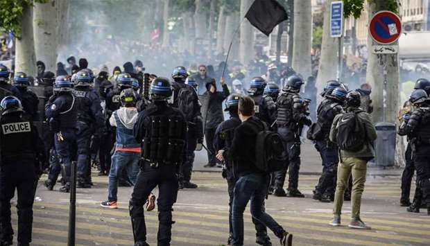 French anti-riot police officers face protesters dressed in black and holding a black flag during an anti-government demonstration called by the ,Yellow Vest, (Gilets Jaunes) movement in Lyon