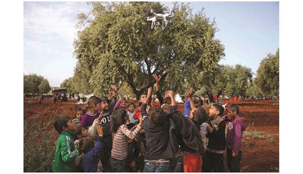 Displaced Syrian children play with a drone in a field near a camp for displaced people in the village of Atme, in the jihadist-held northern Idlib province on May 8. In the olive grove in Atme, dozens of families have spent the night on thin mattresses or blankets laid out over rugs on the red earth. At the base of the trees they have chosen for shelter, they have stored the bare minimum for a life outdoors: bedding, a water cooler, a saucepan, or a cooking gas canister. They have hung up sheets between the trees for a little privacy, and one family has even brought a solar panel.
