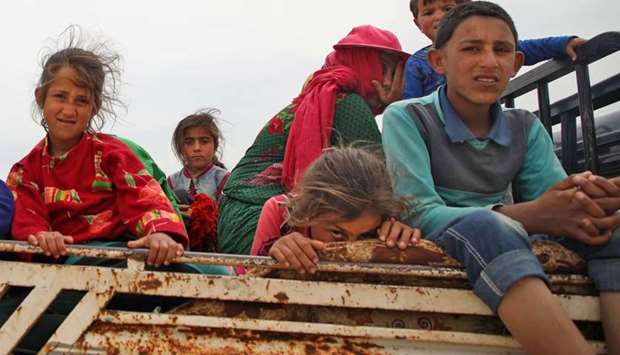 A Syrian family, riding in the back of a truck, flee from reported regime shelling on Hama and Idlib provinces