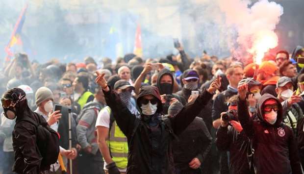 Masked protesters react during clashes with riot police as part of the traditional May Day labour union march with French unions and yellow vests protesters in Paris