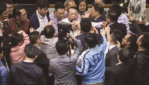 Pro-democracy lawmakers scuffle with pro-Beijing lawmaker Abraham Shek (top centre) in an attempt to seize microphones from him as scuffles break out between lawmakers in the Legislative Council (LegCo) in Hong Kong yesterday.