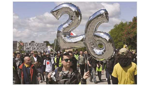 A woman holds balloons representing the number 26 during a demonstration yesterday, called by the u2018yellow vestu2019 (Gilets jaunes) movement in Nantes, western France. u2018Yellow vestu2019 protesters gathered in Paris and other French cities yesterday for the 26th straight week of rallies against the French president.