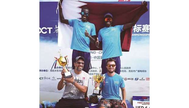 Qataru2019s Ahmed Tijan and Cherif Younousse celebrate with the national flag as coach Mariano Barasetti (bottom left)  and the team physio hold the trophies after winning the Asian title yesterday. At right, the Qatari duo pose with their winning cheque.