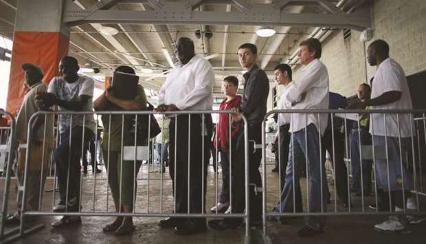People looking for work stand in line to apply for a job during a job fair at the Miami Dolphins Sun Life stadium in Miami, Florida.