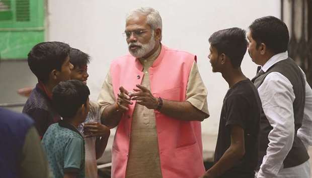 Abhinandan Pathak, a lookalike of Prime Minister Narendra Modi, speaks with youths as he campaigns as an independent candidate in Lucknow.