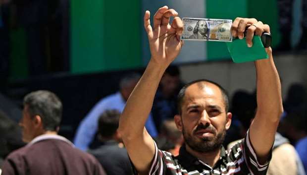 A Palestinian man displays a 100 dollar bill, part of $480 million in aid allocated by Qatar, in Gaz