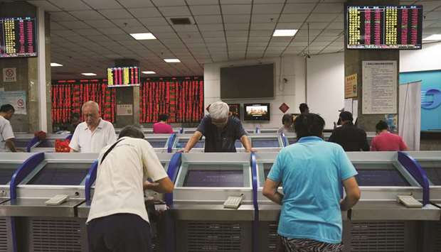 Investors look at computer screens showing stock information at a brokerage house in Shanghai. Shares in China gained 1.9% to 2,938.68 points yesterday.