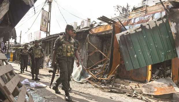 Soldiers walk past a damaged shop after a mob attack in Minuwangoda, near Colombo, yesterday.