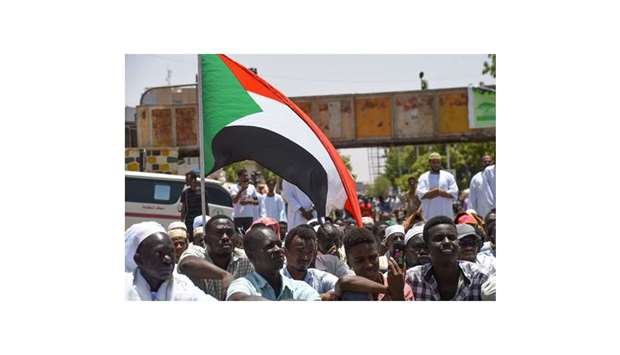 Sudanese protesters wave a national flag as they attend the prayers near the military headquarters in the capital Khartoum, yesterday, during an ongoing sit-in demanding a  civilian-led government transition.