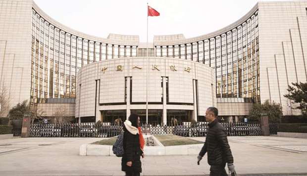 Pedestrians walk past the Peopleu2019s Bank of China headquarters in Beijing. Chinau2019s central bank will use foreign exchange intervention and monetary policy tools to stop the yuan weakening past the key 7-per-dollar level in the near-term, three people familiar with the central banku2019s thinking said.