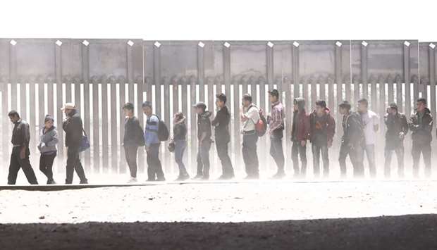 Migrants stand after being detained by Border Patrol on the US side of the border barrier in El Paso, Texas.