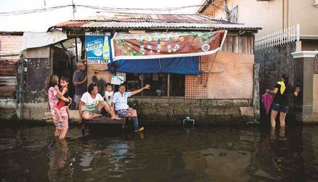 Residents sitting in front of a flooded house in Mabalacat, Pampanga.