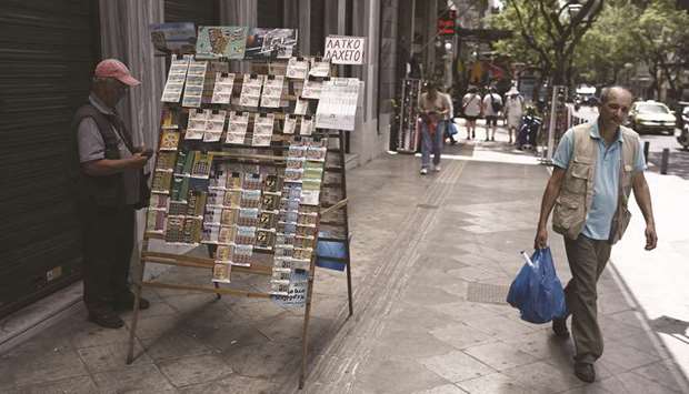A pedestrian passes a street vendor selling lottery tickets on a sidewalk in Athens, Greece, in this file photo.
