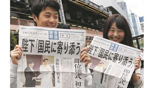 Residents show the extra edition of newspapers reporting Emperor Naruhitou2019s accession in Tokyo yesterday.