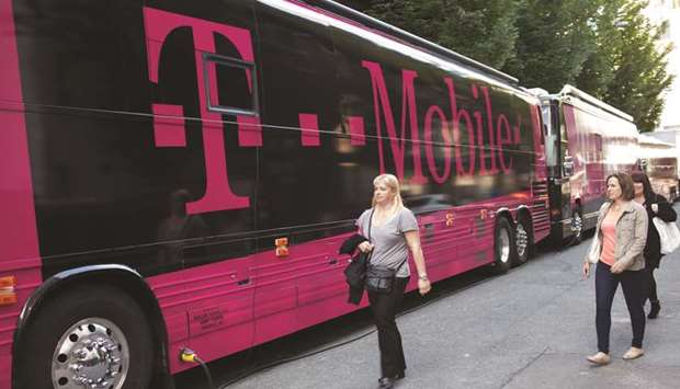 Women walk past buses displaying T-Mobile logos in Seattle, Washington. T-Mobile and Sprint cleared a key hurdle on Monday when Federal Communications Commission Chairman Ajit Pai said he would recommend approval of the $26.5bn merger after the companies offered a package of concessions, including spinning off Sprintu2019s pre-paid brand, Boost, to win regulatorsu2019 blessing.