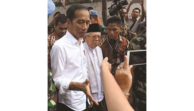 Indonesian President Joko Widodo and his running mate Mau2019ruf Amin (right) greet residents in a neighbourhood in Jakarta yesterday.