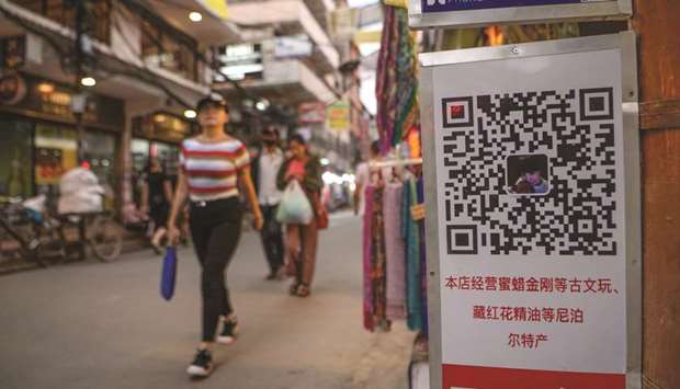 Chinese tourists walk past a QR code for Chinese digital wallets displayed on a street in Kathmandu yesterday.