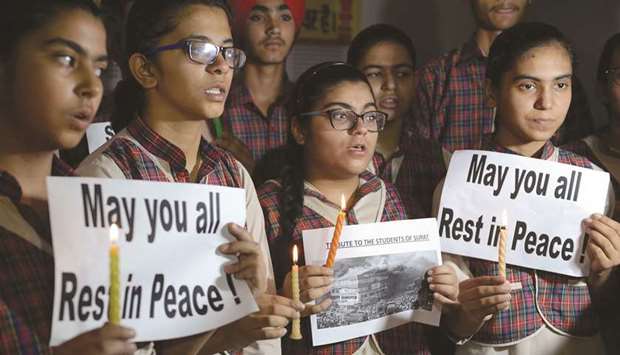 Students hold candles as they pay tribute to the victims of a fire tragedy in Surat, at a school in Amritsar yesterday.