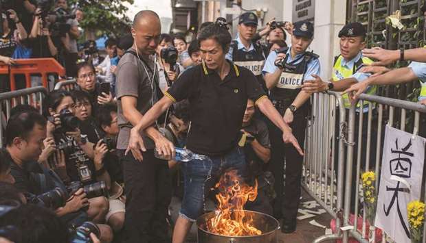 A police officer (left) puts out a fire as pro-democracy activist Lui Yuk-lin burns props outside the Chinese liaison office during a march in Hong Kong to commemorate the June 4, 1989 Tiananmen Square crackdown in Beijing.