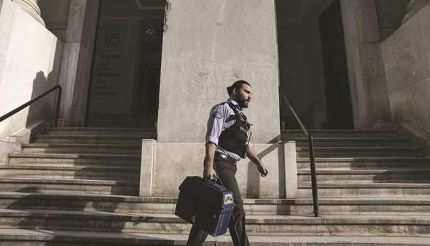 A security guard carries a cash box from the central branch of the National Bank of Greece in Thessaloniki. Using cheaper funds to repay some expensive IMF loans has been a longstanding ambition of the Greek government, as it seeks to bring down its debt refinancing costs.