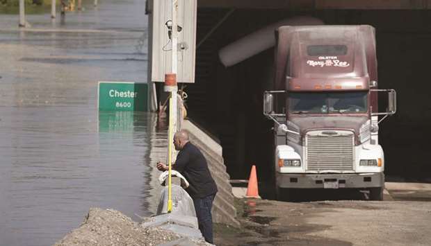 A driver looks over a floodwall as floodwater from the Mississippi River rises while he waits for his truck to be loaded with flour at Ardent Mills in Chester, Illinois.