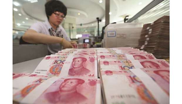 A teller counts yuan notes in a bank in China. The yuan inched lower against the dollar yesterday as market sentiment soured on renewed uncertainty in global trade and fresh signs of weakness in the manufacturing sector.