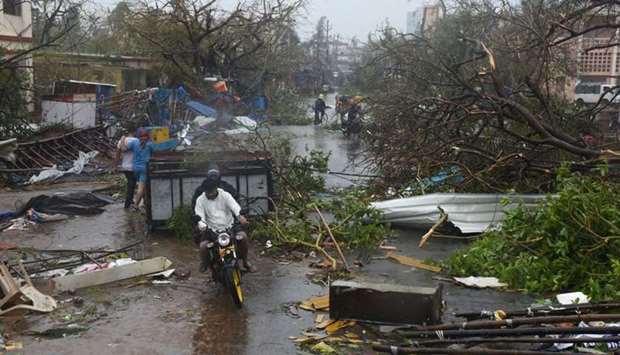 People move through debris on a road after Cyclone Fani hit Puri, in the eastern state of Odisha, In