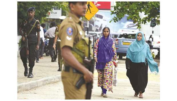 Armed security personnel stand guard as women walk on a street in Colombo yesterday.