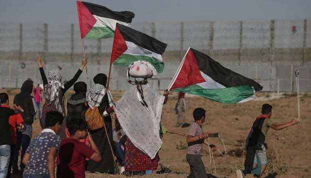 Palestinian protesters wave national flags during a demonstration along the border fence with Israel, east of Gaza City