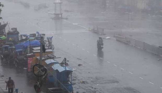 Indian residents ride a bike along a road after Cyclone Fani landfall yesterday in Puri in the eastern Indian state of Odisha