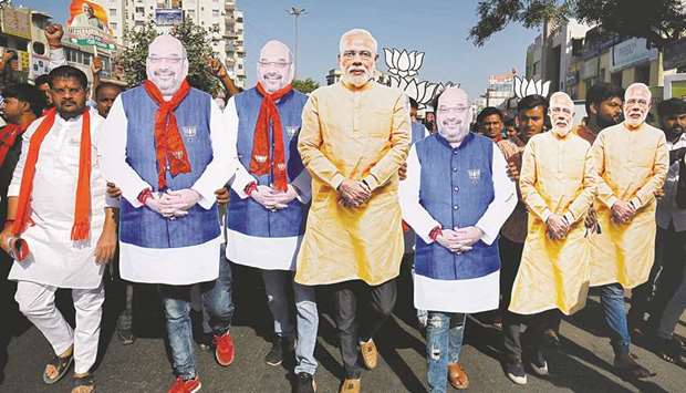 Supporter of Indiau2019s ruling Bharatiya Janata Party (BJP) wearing cut-outs of Prime Minister Narendra Modi and the party president Amit Shah walk during an election campaign in Ahmedabad on April 11.