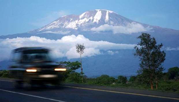 A vehicle drives past Mount Kilimanjaro in Tanzania's Hie district