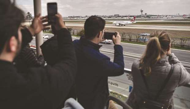 People take pictures of Turkish Airlines planes from a terrace of the Ataturk Airport in Istanbul on April 4. The Istanbul-based carrier has sent a request for proposals to banks for options including a conventional bond or sukuk, according to two people with knowledge of the matter.