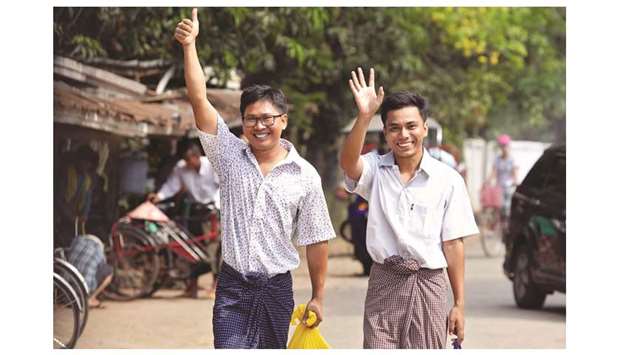 Reuters journalists Wa Lone (left) and Kyaw Soe Oo gesture as they walk to Insein prison gate after being freed in a presidential amnesty in Yangon yesterday.